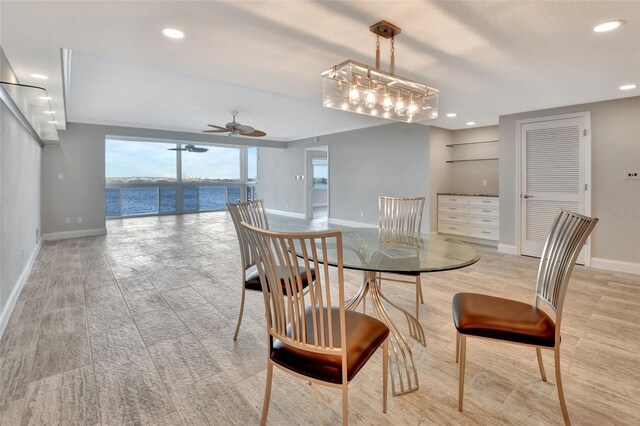 dining space featuring a water view and ceiling fan with notable chandelier