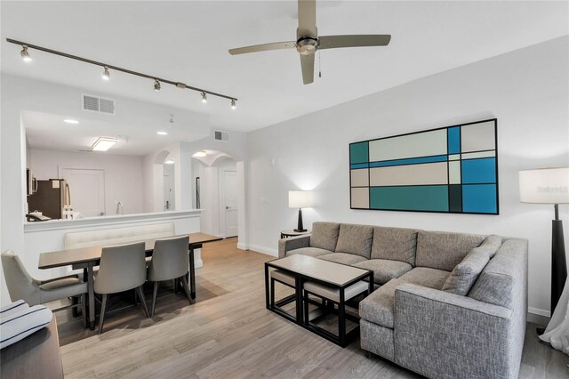 living room with light hardwood / wood-style flooring, ceiling fan, and rail lighting