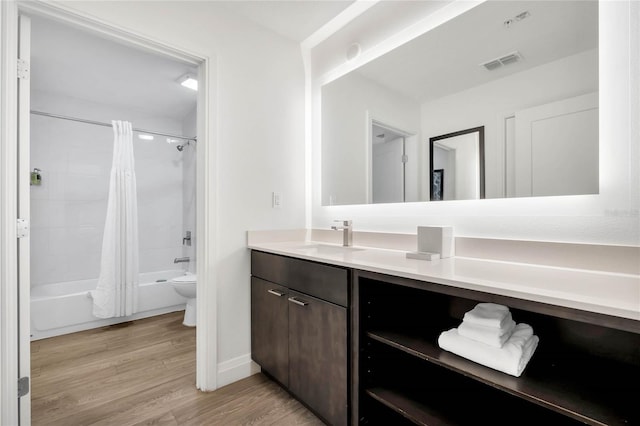 full bathroom with vanity, wood-type flooring, shower / bath combo with shower curtain, and toilet