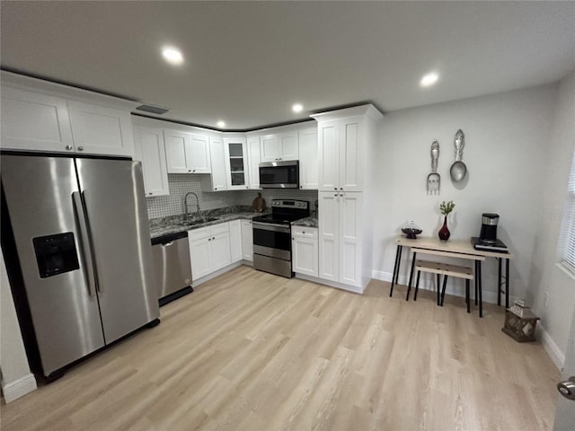 kitchen with tasteful backsplash, light hardwood / wood-style floors, stainless steel appliances, and white cabinetry