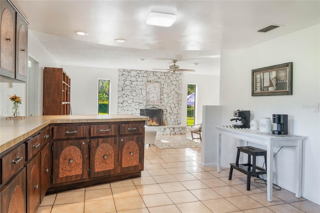 kitchen featuring ceiling fan, a fireplace, plenty of natural light, and light tile patterned flooring