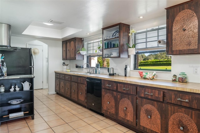 kitchen featuring light tile patterned flooring, sink, dark brown cabinets, a raised ceiling, and black appliances