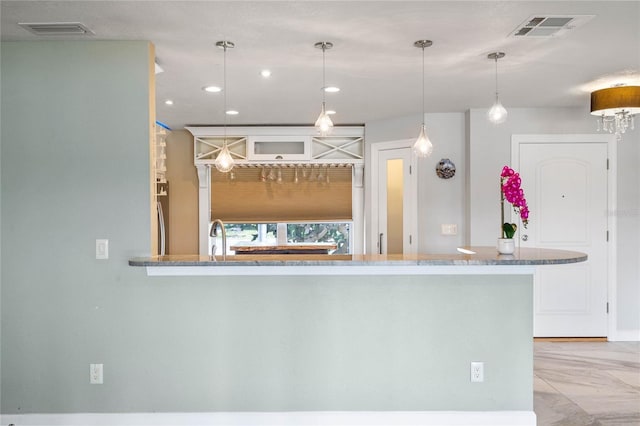 kitchen featuring decorative light fixtures, kitchen peninsula, and stainless steel refrigerator