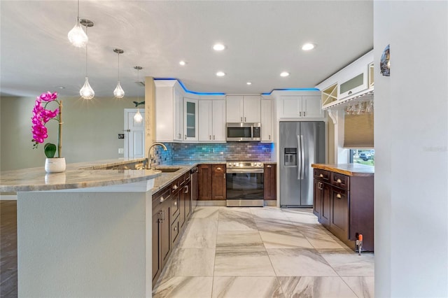 kitchen with pendant lighting, appliances with stainless steel finishes, white cabinetry, kitchen peninsula, and dark brown cabinets