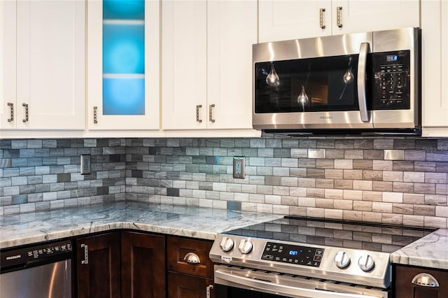 kitchen featuring appliances with stainless steel finishes, white cabinets, light stone countertops, decorative backsplash, and dark brown cabinetry