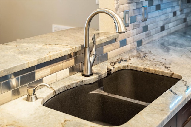 details with decorative backsplash, sink, and light stone countertops