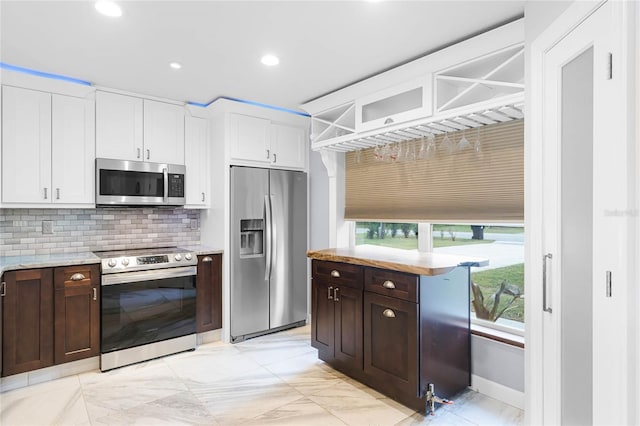 kitchen featuring white cabinets, stainless steel appliances, dark brown cabinets, and tasteful backsplash