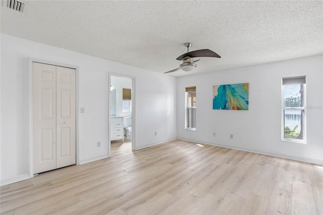 unfurnished bedroom featuring ceiling fan, connected bathroom, a textured ceiling, and light wood-type flooring