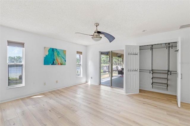 unfurnished bedroom with light wood-type flooring, ceiling fan, access to exterior, and a textured ceiling