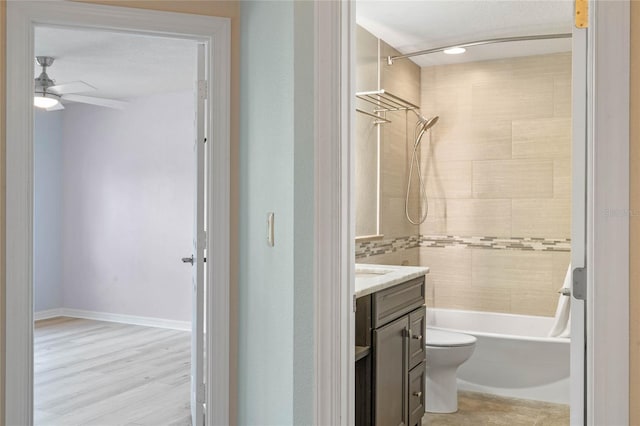 full bathroom featuring wood-type flooring, ceiling fan, tiled shower / bath, toilet, and vanity