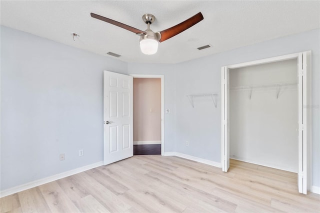 unfurnished bedroom featuring ceiling fan, a textured ceiling, a closet, and light wood-type flooring