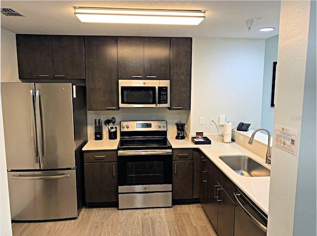 kitchen with stainless steel appliances, light hardwood / wood-style floors, and sink