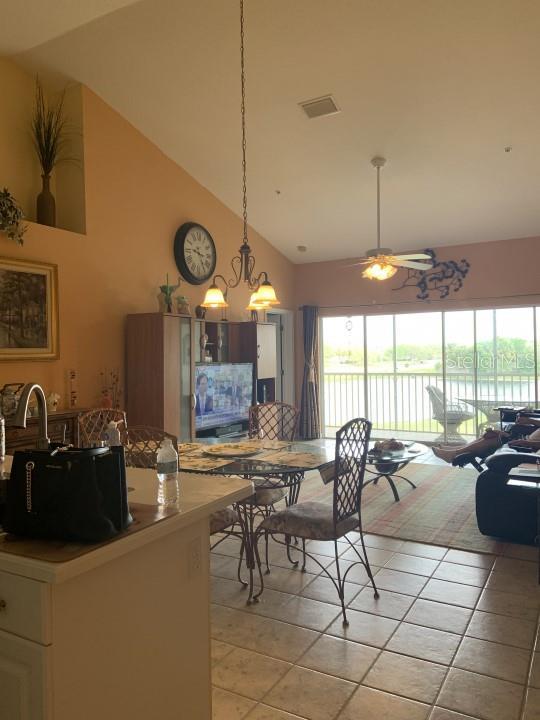 dining room featuring ceiling fan with notable chandelier, a wealth of natural light, light tile patterned flooring, and high vaulted ceiling