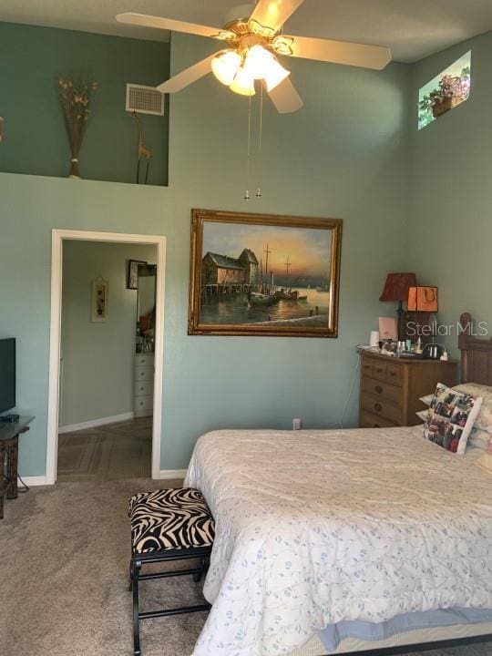 bedroom featuring carpet, ceiling fan, and a towering ceiling