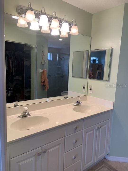 bathroom featuring vanity, toilet, and a shower with door