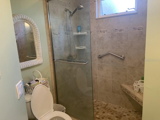 bathroom featuring a shower with door and toilet