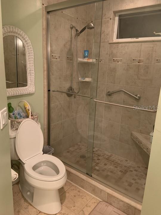 bathroom featuring toilet and a shower with door