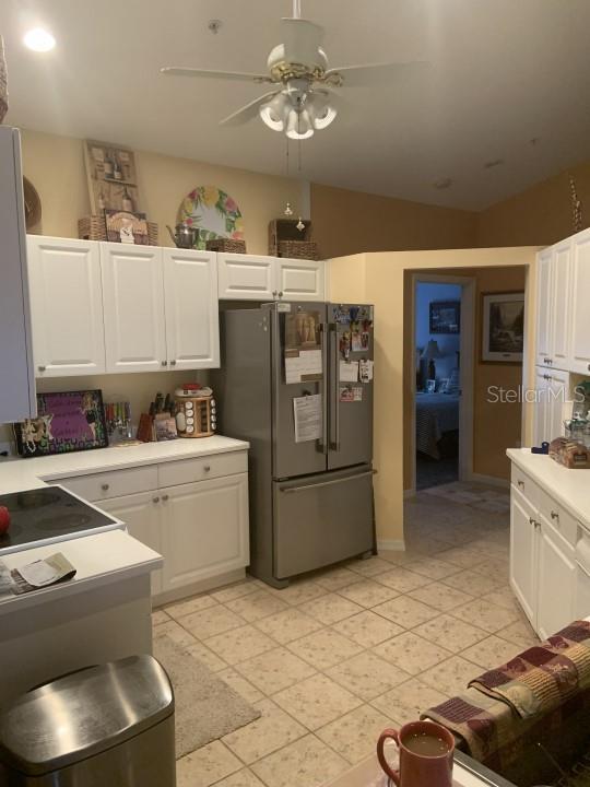 kitchen featuring stovetop, stainless steel fridge, white cabinetry, and ceiling fan