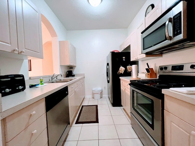 kitchen with white cabinetry, appliances with stainless steel finishes, sink, and light tile patterned floors