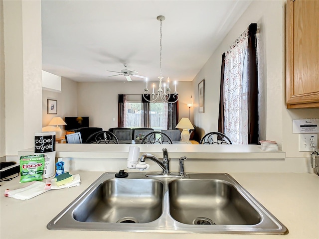 kitchen featuring hanging light fixtures, ceiling fan with notable chandelier, and sink