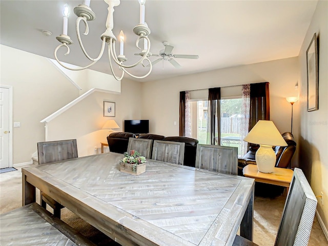 dining space with ceiling fan with notable chandelier and light colored carpet