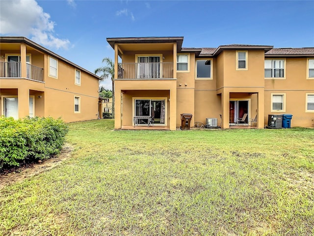 back of property with a lawn, a balcony, and central air condition unit