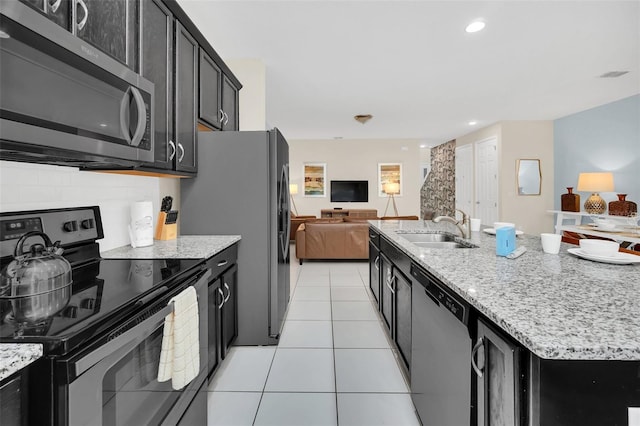 kitchen featuring light stone counters, sink, an island with sink, appliances with stainless steel finishes, and light tile patterned floors