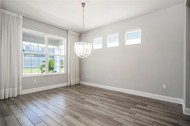 empty room with a chandelier and dark hardwood / wood-style flooring