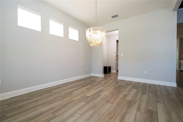 unfurnished room with an inviting chandelier and hardwood / wood-style floors