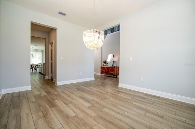 unfurnished dining area with a notable chandelier and light wood-type flooring