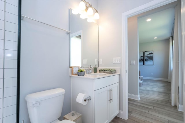 bathroom featuring toilet, vanity with extensive cabinet space, and hardwood / wood-style floors