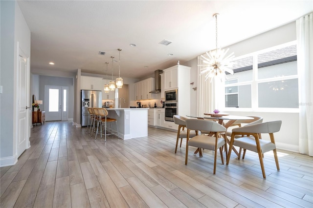 dining area featuring sink, light wood-type flooring, and an inviting chandelier