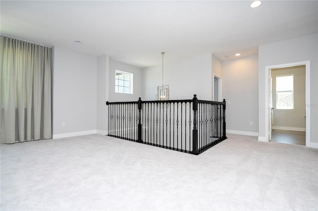 carpeted spare room with a chandelier