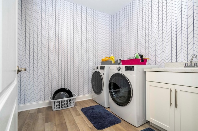 laundry area featuring light hardwood / wood-style floors, washing machine and dryer, and cabinets