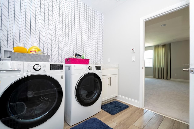 laundry area featuring light carpet, washing machine and dryer, and cabinets