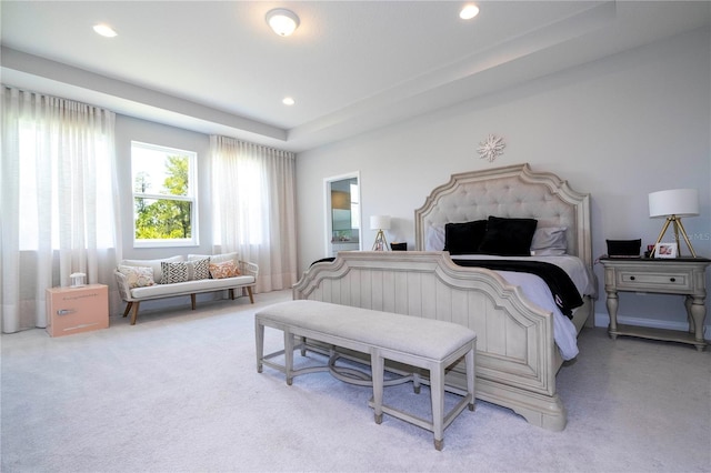 bedroom with light carpet and a tray ceiling