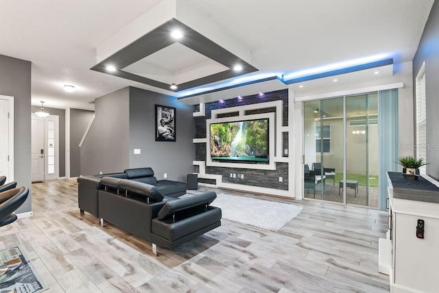 home theater featuring a wealth of natural light, a tray ceiling, and light hardwood / wood-style flooring