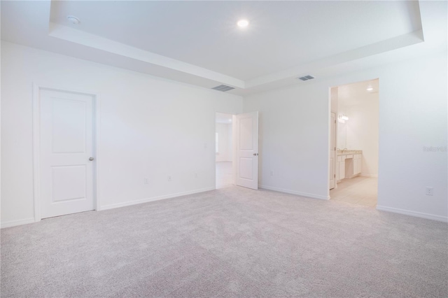 unfurnished room with light carpet and a tray ceiling