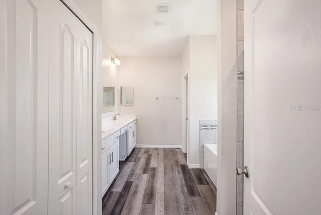 bathroom featuring hardwood / wood-style flooring, vanity, and a washtub