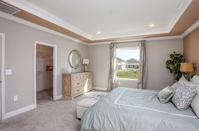 bedroom featuring light carpet, a spacious closet, crown molding, and a raised ceiling