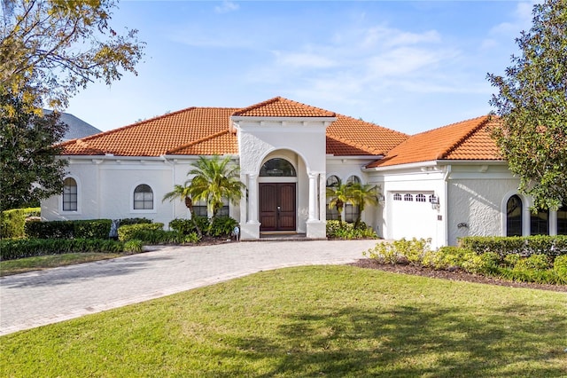 mediterranean / spanish house featuring a front yard and a garage