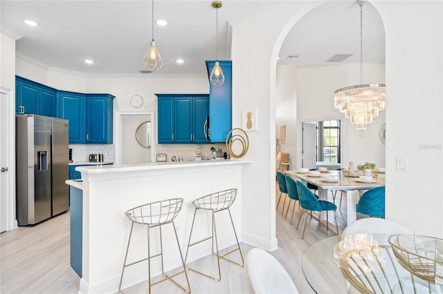 kitchen featuring blue cabinets, kitchen peninsula, stainless steel fridge, decorative backsplash, and light wood-type flooring