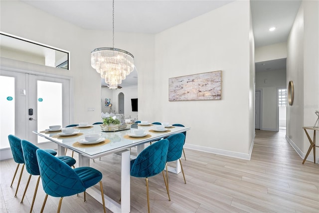 dining space with light hardwood / wood-style floors and a notable chandelier