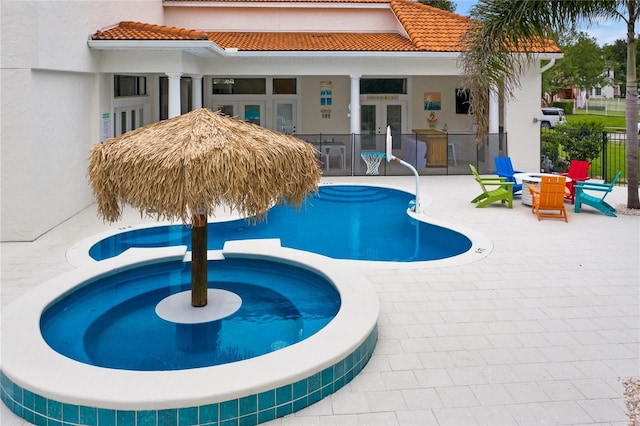 view of pool with exterior bar, an in ground hot tub, french doors, and a patio