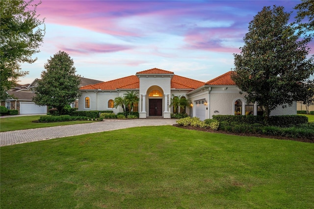 mediterranean / spanish-style house with a garage and a lawn