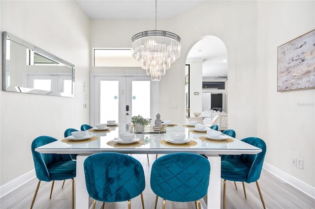 dining room featuring light wood-style floors, baseboards, and an inviting chandelier