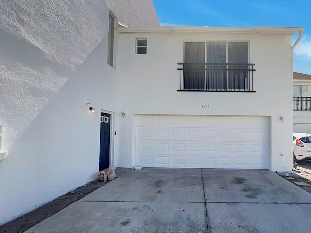 view of front of home with stucco siding, concrete driveway, and an attached garage