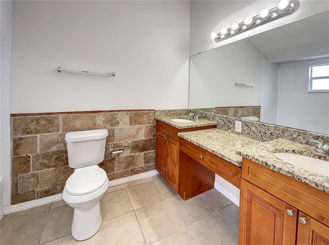 bathroom with a sink, toilet, double vanity, and tile patterned flooring