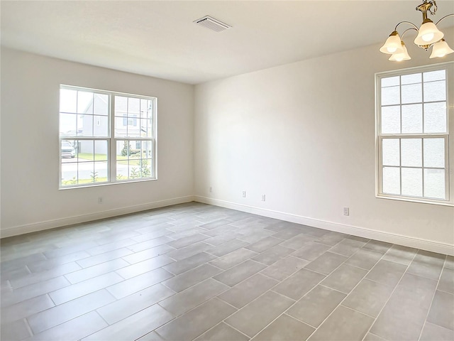 empty room with a healthy amount of sunlight and an inviting chandelier