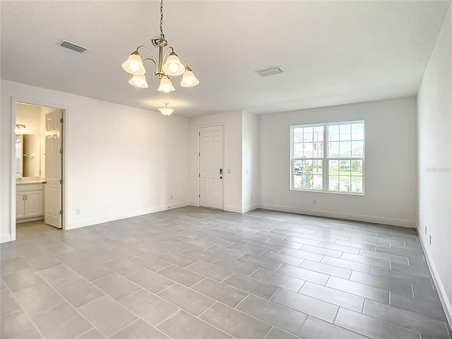 empty room with tile patterned floors and a notable chandelier